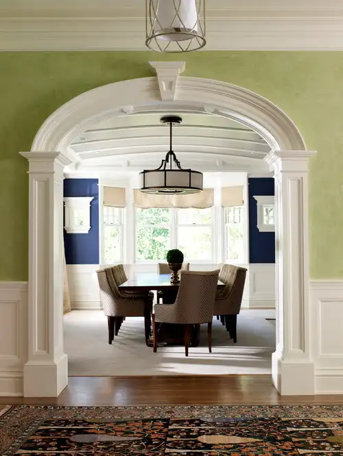Dining room framed by wall with green paint and white crown molding.