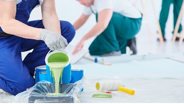 Person pouring paint into a container.