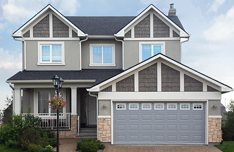 The exterior of a two-story gray house with white siding and a garage.