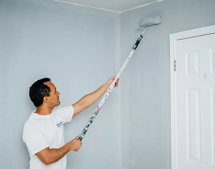 A Five Star Painting house painter using a paint roller on the wall of a room